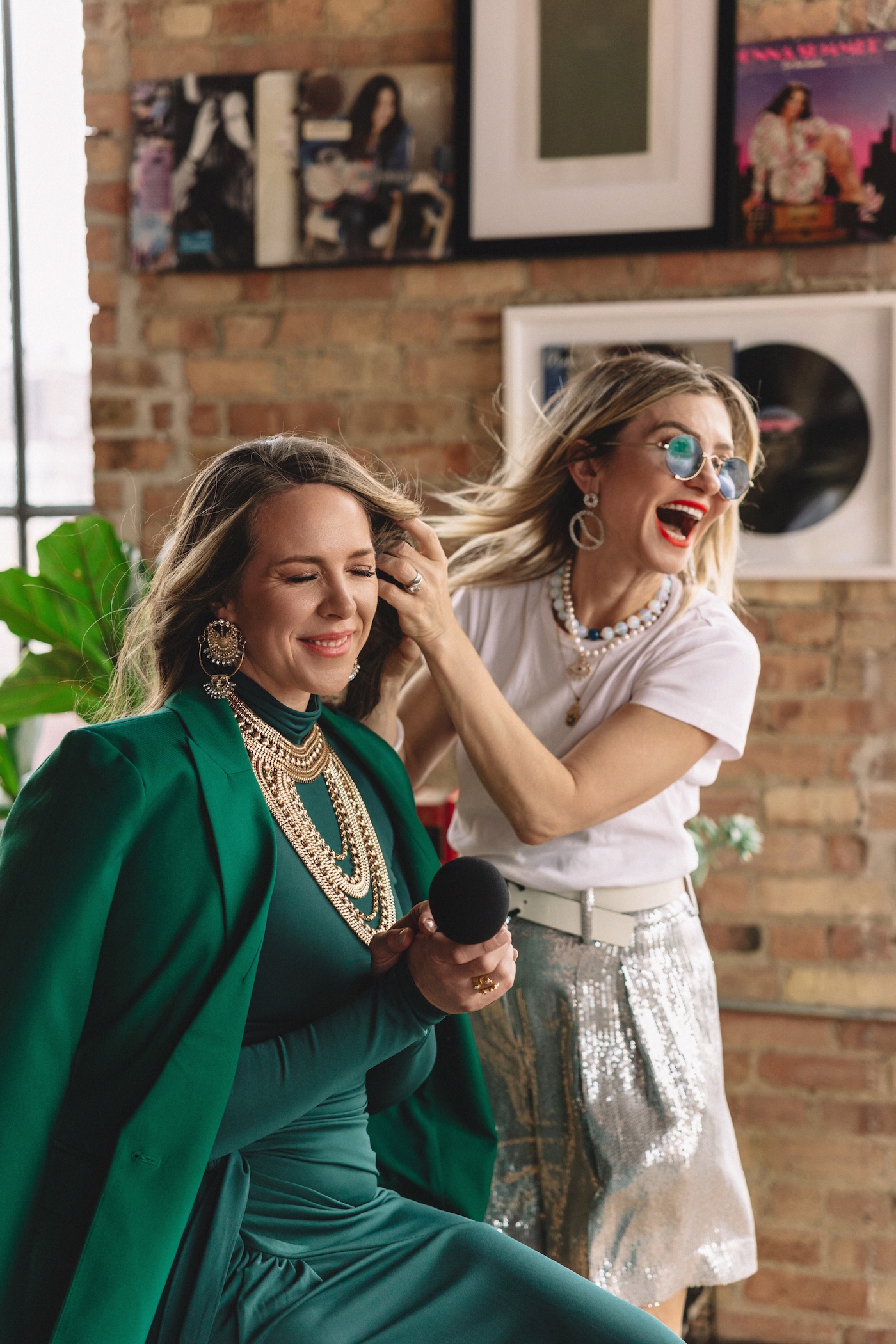 Tali Kogan styling a woman in a green gown and layered gold jewellery in a studio.